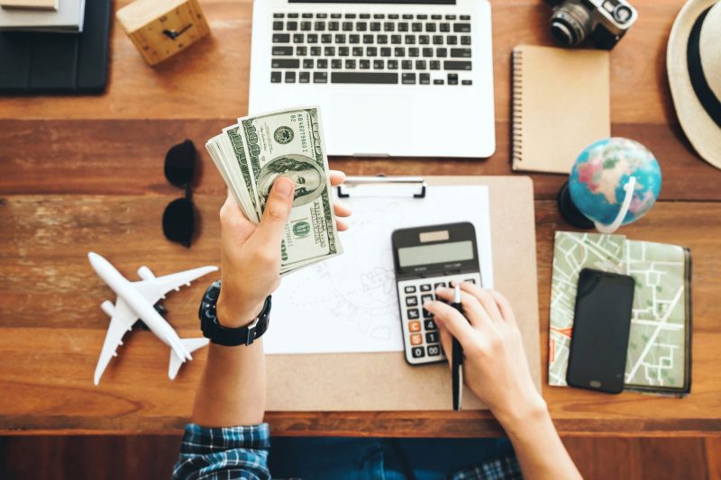 A traveler using a budgeting app to track expenses while planning a trip, highlighting the importance of managing travel expenses.