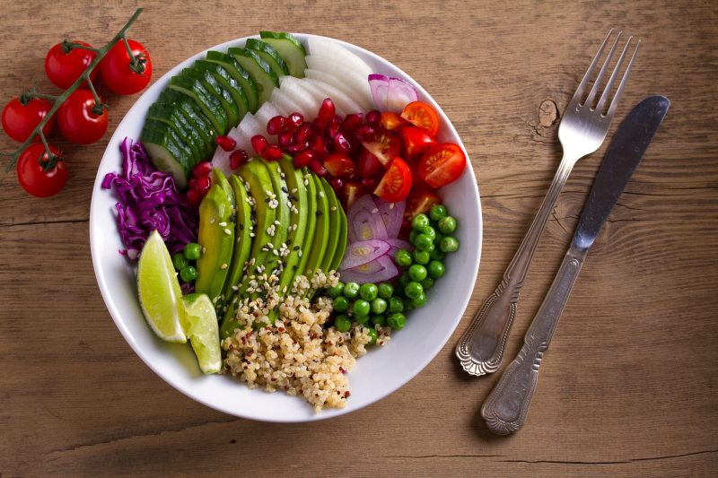 Traveler holding a plant-based meal while exploring a vibrant local market, surrounded by fresh fruits and vegetables